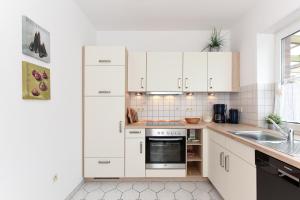 a kitchen with white cabinets and a sink at Ferienwohnung Kapitän in Carolinensiel