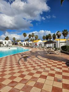 a resort with a checkered tile floor and a swimming pool at Casa Azul Montecastillo L7 in Caleta De Fuste