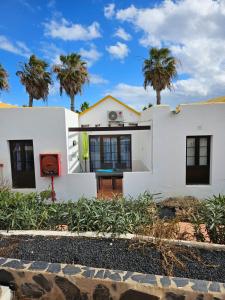 una casa blanca con palmeras en el fondo en Casa Azul Montecastillo L7 en Caleta de Fuste