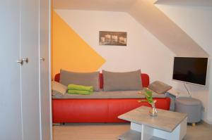 a living room with a red couch and a tv at Ferienwohnung Meersburg 30m vom Bodensee in Meersburg