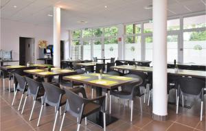 uma sala de jantar com mesas, cadeiras e janelas em Cozy Apartment In quemauville With Heated Swimming Pool em Équemauville