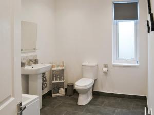 a white bathroom with a toilet and a sink at Bracken Dene in Cresswell