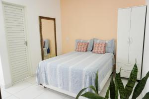 um quarto com uma cama com almofadas azuis e cor-de-rosa em Temporada Cuiabana em Cuiabá