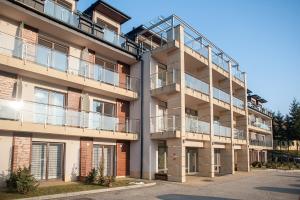 un edificio de apartamentos con balcones y aparcamiento en Apartamenty Czerwone Maki Wisła, en Wisła
