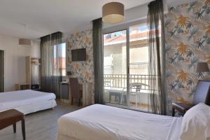 Una habitación de hotel con dos camas y balcón. en Hotel Marbella, en Biarritz