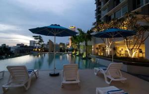 un groupe de chaises et de parasols à côté d'une piscine dans l'établissement Meta @ Swiss Garden Residence KL Bukit Bintang, à Kuala Lumpur