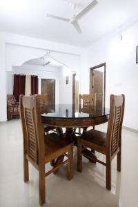 a dining room with a wooden table and chairs at THEKKADY HOMES in Thekkady
