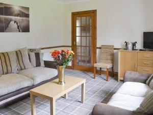 a living room with two couches and a table with flowers at Nursery Cottage - Beaufort Estate in Kiltarlty