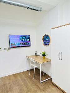 een kamer met een tafel en een tv aan de muur bij The Grand M London city in Londen