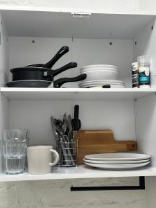 un estante con platos y utensilios en la cocina en The Grand M London city, en Londres