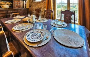 einem Holztisch mit Tellern und Geschirr darauf in der Unterkunft Pet Friendly Home In Saint-brice-de-landell With Kitchen in Saint-Brice-de-Landelles