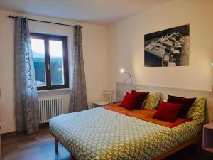 - une chambre avec un lit doté d'oreillers rouges et une fenêtre dans l'établissement Casa Maria, à Ledro