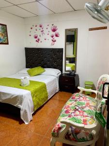 1 dormitorio con cama, silla y espejo en Hotel Mi Casita Pereira, en Pereira