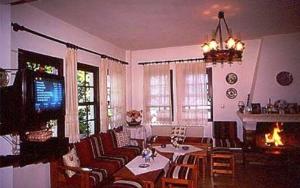a living room with a table and chairs and a television at Hotel Sevilli in Agios Ioannis Pelio
