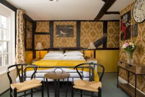 1 dormitorio con 1 cama, 2 sillas y reloj en The Sun Hotel en Canterbury