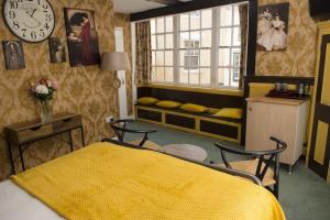 une chambre avec un lit jaune et une horloge sur le mur dans l'établissement The Sun Hotel, à Canterbury