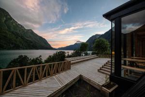 a house with a wooden walkway next to a lake at Tawa Refugio del Puelo in Puelo