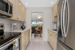 a kitchen with white cabinets and a stainless steel refrigerator at Beach Luxury 805 in Naples