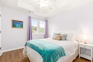 een witte slaapkamer met een bed en een raam bij Village Place 6B - Bella Tybee in Tybee Island