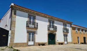 - un bâtiment blanc avec une porte verte et des balcons dans l'établissement Casa do Terreiro, à Barqueiros