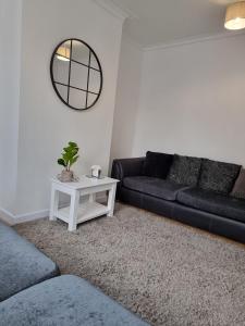 a living room with a black couch and a table at 23 Woodhouse in Stoke on Trent