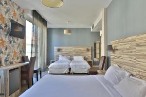 ビアリッツにあるブリット ホテル マルベーリャのベッド2台とデスクが備わるホテルルームです。