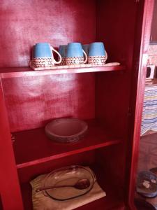 un armario rojo con tres tazas y tazones azules en CASA PARA ALQUILER LA LILI en Uspallata
