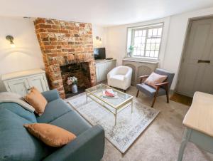 a living room with a blue couch and a brick fireplace at June Cottage in Bognor Regis