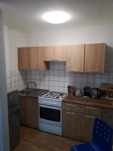 La cuisine est équipée de placards en bois et d'une cuisinière blanche. dans l'établissement Apartament przy dworcu, à Krosno