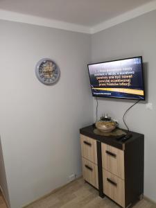 Pokój z telewizorem i zegarem na ścianie w obiekcie Apartament przy dworcu w Krośnie