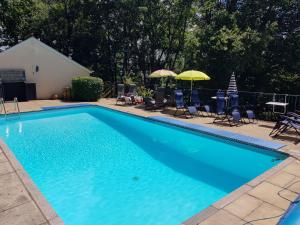 a large blue swimming pool with chairs and umbrellas at Woodside Oak hot tub & pool sleeps 4-6 in Bideford