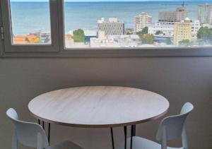 una mesa y sillas frente a una ventana en Infinito - Departamento con vista al mar en Comodoro Rivadavia