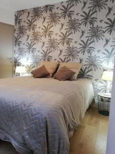 Un dormitorio con una cama con una pared con palmeras. en La petite maison de Marie, en Licques