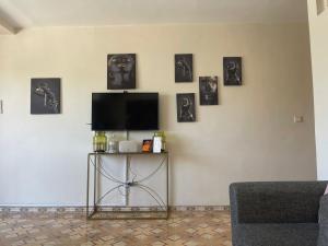 een woonkamer met een tv en foto's aan de muur bij Cosy appartement au super centre ville avec vue partielle sur le parc in Agadir