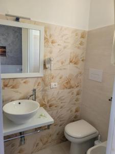 een badkamer met een wastafel, een toilet en een spiegel bij La Carcara in Otranto