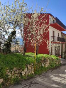 um edifício vermelho e branco com uma árvore em frente em La casetta in montagna em Torricella Peligna