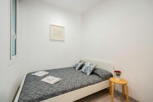 a bed in a white room with a table at SAGRADA FAMILIA C&D Lovely Apartment in Barcelona