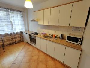 cocina con armarios blancos, fregadero y microondas en Green Kabaty Apartment 2, en Varsovia