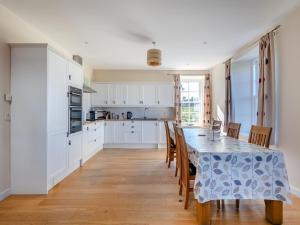 una cocina con armarios blancos y una mesa con sillas. en Meadowgreen Farmhouse, en Forfar