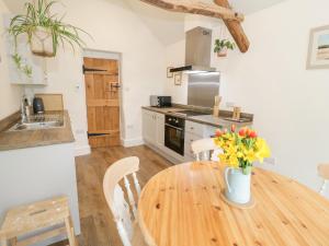 a kitchen with a wooden table with flowers in a vase at The Old Stable in Conwy