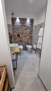 La salle de bains est pourvue de 2 lavabos, de toilettes et d'un mur en briques. dans l'établissement Home Catania Dante Accommodations, à Catane