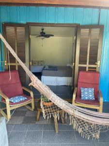 eine Hängematte auf einer Veranda mit 2 Stühlen und einem Bett in der Unterkunft Casa da Ilha do Mel - Pousada de Charme in Ilha do Mel