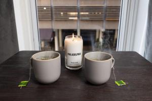 two cups of coffee with a candle on a table at Thena Hotel 2nd Floor Studio Unit4 in Philadelphia