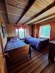- une chambre avec 2 lits dans une cabane en rondins dans l'établissement Hermosa cabaña en Lago Ranco, à Lago Ranco