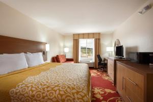 a hotel room with a bed and a television at Days Inn & Suites by Wyndham Caldwell in Caldwell