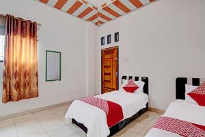 two beds in a room with white walls and a window at OYO 92455 Hadhilfa Homestay Syariah in Pekanbaru