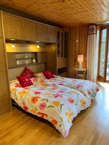 een slaapkamer met een groot bed en een kleurrijk dekbed bij Heida, studio ensoleillé au village avec magnifique vue sur la Dent-Blanche in Evolène