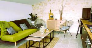 ein Wohnzimmer mit einem grünen Sofa und Stühlen in der Unterkunft Gîte de la Petite vallée in Saint-Savinien