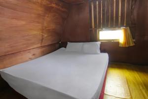 a large white bed in a small room with a light at SPOT ON 92462 Awenk Homestay in Lombok