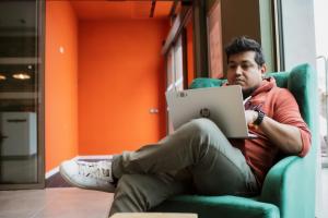 a man sitting in a chair with a laptop at easyHotel Paris Nord Aubervilliers in Aubervilliers